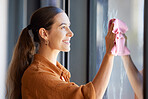 Woman cleaning window or wipe glass with a cloth in an apartment, home or house and washing bacteria. Disinfection, hygiene and smiling female removing dirt or dust in an office by doing housework