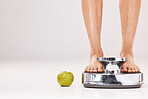 Feet, scale and apple in studio on a gray background with mockup for diet, weightloss or detox. Food, weightscale and healthy eating with a barefoot woman weighing herself to tracl body progress