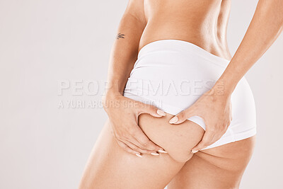 Buy stock photo Hands, butt and underwear with a woman model in studio on a gray background squeezing cellulite from the back. Liposuction, wellness and heath with a female touching her buttocks or ass in panties