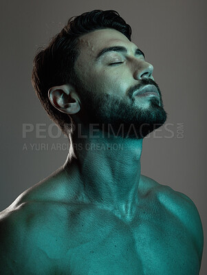 Buy stock photo Man, face and neon with beauty and skincare, grooming and wellness with eyes closed against studio background. Healthy skin, relax in blue light and peace, self care and cosmetic facial and treatment