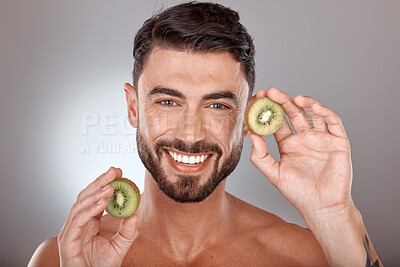 Buy stock photo Man, face and beauty with kiwi, facial care with wellness and organic treatment against studio background. Natural skincare, exotic fruit and wellness with cosmetic care and smile in portrait