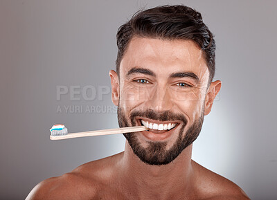 Portrait, man and toothbrush with smile, wellness and on grey studio background. Dental hygiene, male or mouth health with toothpaste, fresh breath or brushing teeth for oral cleaning or healthcare