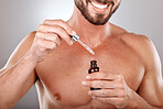 Hand, product and serum with a man model in studio on a gray background holding a glass bottle. Beauty, skincare and antiaging with a male inside to apply oil to his body for natural treatment
