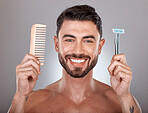 Portrait, shaving and comb with a man model holding a razor in studio on a gray background for skincare. Face, wellness and hands with a handsome young male in the bathroom to shave his beard