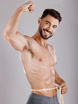 Buy stock photo Portrait, body and weightloss with a man measuring his waist in studio on a gray background for diet progress. Fitness, heath and wellness with a topless male model flexing his strong bicep muscle
