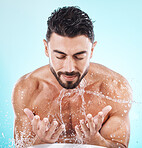 Man, water splash and face cleaning in blue background studio for grooming hygiene, skincare wellness and cosmetics dermatology care. Model hands, facial and body washing or morning beauty routine