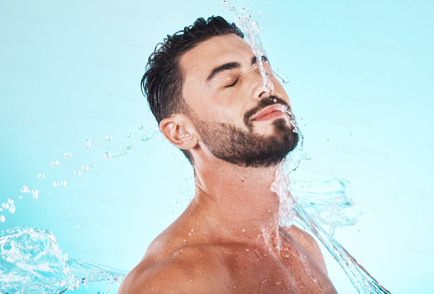 Buy stock photo Water, splash and skincare with face of man for shower, self care and natural cosmetics. Luxury, hydration and refreshing with model for dermatology, wellness and cleaning in blue background studio