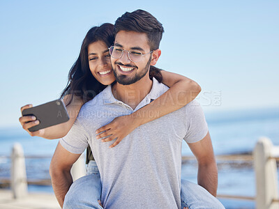 Buy stock photo Phone selfie, ocean and couple hug, bond and enjoy time together for peace, freedom or romantic date. Sea beach, memory photo and man piggyback woman on fun travel holiday in Rio de Janeiro Brazil