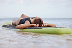 Relax, woman or surfer on water at a beach on holiday vacation resting on a surfboard in Bali. Freedom, thinking or healthy sports girl relaxing body in calm nature, sea or peaceful ocean in summer 