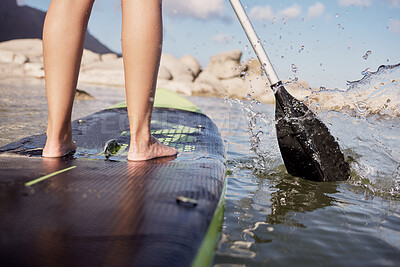 Buy stock photo Feet, paddle surf and water with a sports woman standing on a paddle board in the sea, ocean or a river outdoor. Back, balance and sport with a female athlete outside for fitness, exercise or hobby