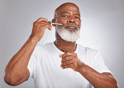 Buy stock photo Senior man, face serum and skincare with dermatology and cosmetics for clean, glow and fresh skin. Portrait of a black male with a pipette for collagen oil on a grey studio background for beauty