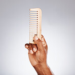 Hand, wood comb and studio for beauty, grooming and self care cosmetics by grey background. Black man, organic wooden product and recycle material for wellness, skincare and hair care with self love