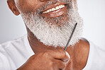 Elderly, black man with comb for beard, beauty and grooming zoom with face hygiene and cosmetic care. Hair care closeup, brush body hair and treatment with cosmetics  against studio background