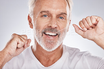 Buy stock photo Face, dental floss and senior man in studio isolated on a gray background. Portrait, cleaning and elderly male model with product flossing teeth for oral wellness, tooth care and healthy gum hygiene 