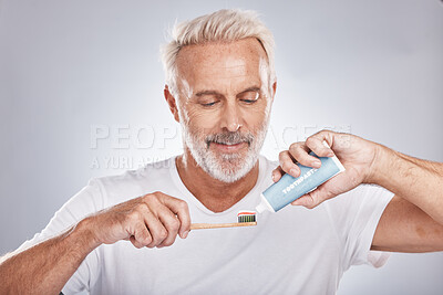 Buy stock photo Face, toothpaste and senior man with toothbrush in studio isolated on a gray background. Hygiene, cleaning and elderly male model holding product for brushing teeth, dental wellness and healthy gums.