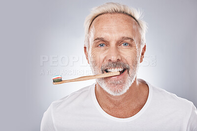 Grooming, dental hygiene and man brushing teeth for mouth health, happy smile and clean teeth on a studio background. Healthcare, oral care and face portrait of a senior model with a toothbrush