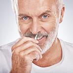 Portrait, tweezers and nose with a senior man in studio on a gray background for grooming or personal hygiene. Face, hand and equioment with a mature male tweezing to remove nasal hair in a bathroom