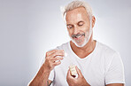 Man, skincare or face oil on studio background in mature self care, product healthcare or aging wellness. Smile, happy  model or facial serum for beard growth, beauty collagen or senior dermatology