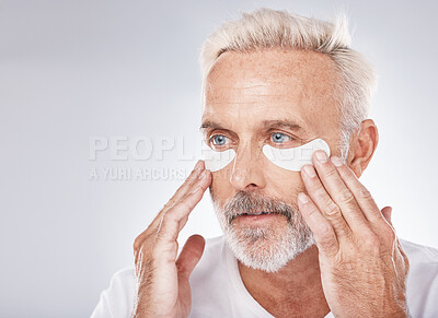 Buy stock photo Skincare, eyes patch and man in studio for dermatology facial, face cosmetics or collagen mask advertising or marketing mockup. Senior model, hands application and eye patches or anti aging product
