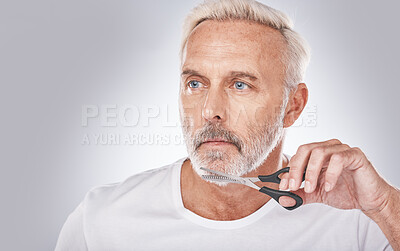Buy stock photo Facial hair, cutting and man with scissors for grooming, shaping and routine treatment on a studio background. Barber, cleaning and face of a senior model trimming beard during morning clean