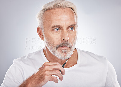 Buy stock photo Scissors, wellness and man cutting beard on face for morning routine, grooming and cosmetic hygiene on a studio background. Barber, skincare and senior model trimming facial hair for clean beauty