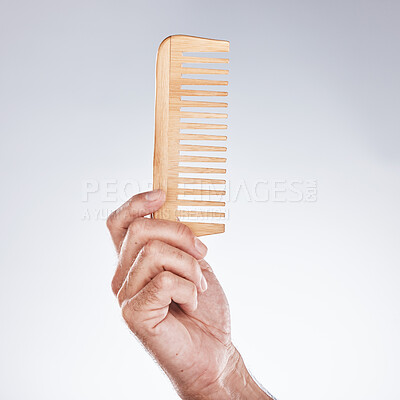 Buy stock photo Hand, comb and haircare with a man barber in studio on a gray background for grooming or hair styling. Salon, bamboo and beauty with a male hairdresser holding a tool to groom or style closeup indoor