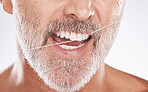 Floss, dental and face of senior man in studio isolated on a gray background. Cleaning, hygiene and elderly male model with product flossing teeth for oral wellness, tooth care and healthy mouth.