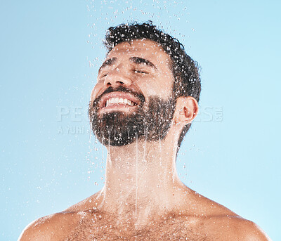 Buy stock photo Man, shower and water for cleaning, studio and self care wellness with smile by blue background. Model, skincare and water splash on face, cold and self love for health, body and clean by backdrop 