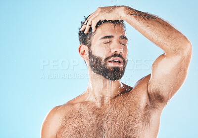 Buy stock photo Water, bathroom and a man cleaning his hair with shampoo in studio on a blue background for beauty. Hygiene, washing and a handsome male wet with droplets in the shower while bathing for haircare