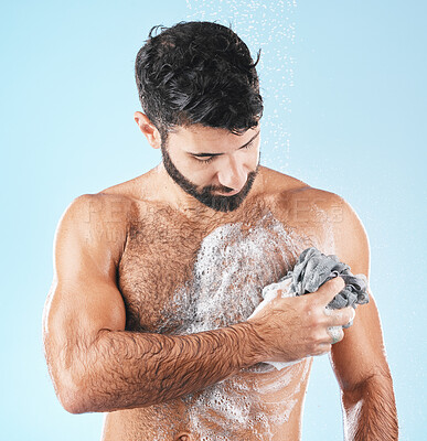 Buy stock photo Washing body, skincare and man cleaning for hygiene, natural health and shower on a blue studio background. Morning routine, soap and healthy model showering to clean skin with a cloth and water