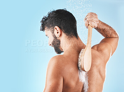 Buy stock photo Shower, man and soap for body cleaning with brush in blue background studio, grooming hygiene and skincare wellness. Model, water and luxury spa body care, dermatology and self care morning routine