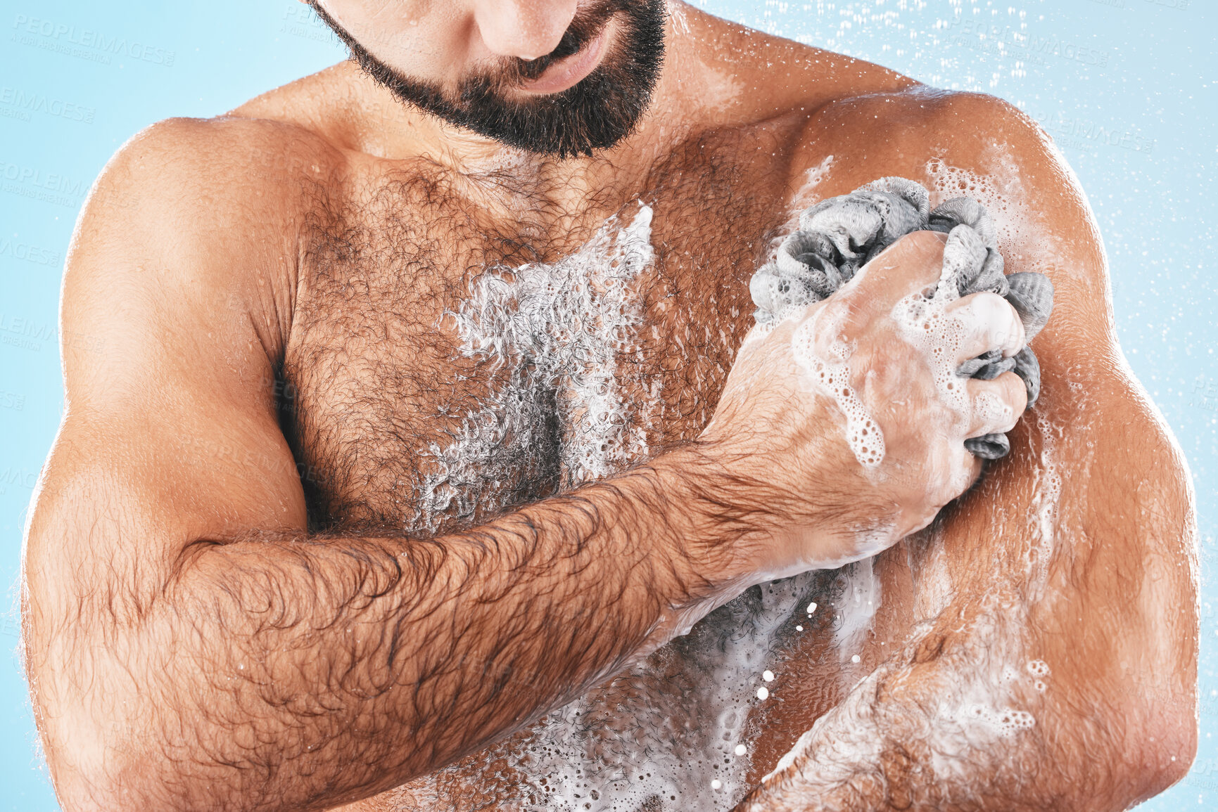 Buy stock photo Shower, soap and man washing body for hygiene, cleaning health and fresh morning on a blue studio background. Skincare, water and cosmetics model showering to clean skin for healthy lifestyle