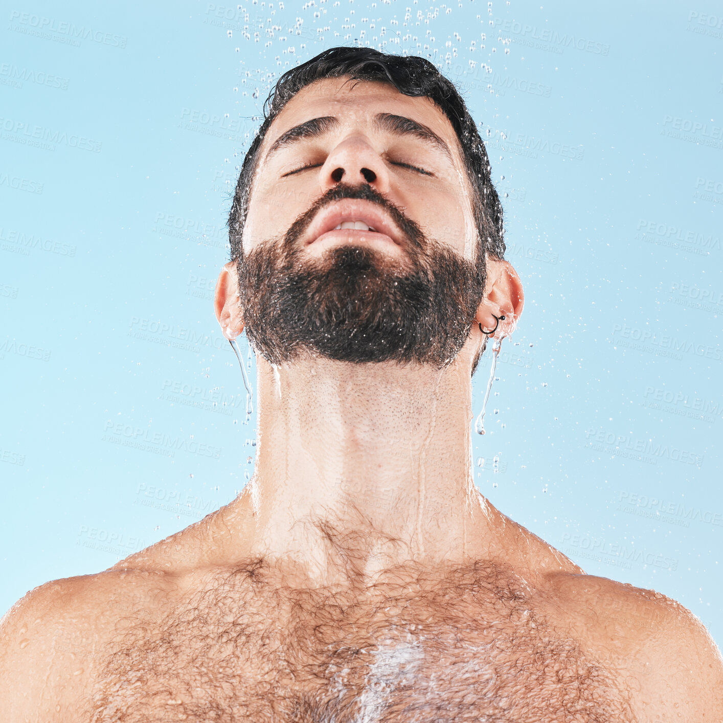 Buy stock photo Man in shower, water and clean body with hygiene, grooming and skincare against blue studio background. Cleaning face, model with water drops and facial, natural treatment and cosmetic mockup