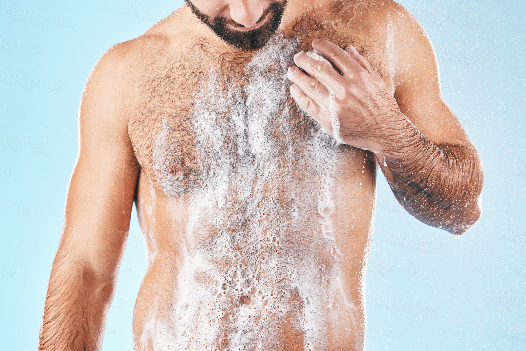 Buy stock photo Shower, water and man with soap on body for cleaning, washing and hygiene on blue background studio. Grooming, bathroom and torso of male with foam sponge for skincare, spa wellness and body care