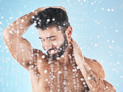 Buy stock photo Water splash, face and man in shower for skincare in studio isolated on a blue background. Water drops, dermatology and male model cleaning, washing or bathing for wellness, healthy skin and hygiene.
