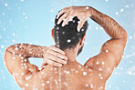 Face, back and water splash of man in shower in studio on a blue background. Water drops, dermatology and male model washing, cleaning or bathing for fresh hygiene, skincare wellness or healthy skin.