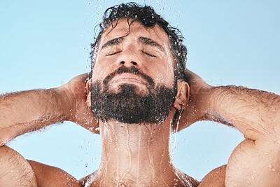 Buy stock photo Face, water splash and man in shower for skincare in studio isolated on a blue background. Dermatology, water drops and male model cleaning, bathing or washing for healthy skin, hygiene and wellness.