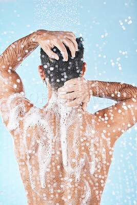 Buy stock photo Shower, water and man cleaning body with soap, foam and hair products on blue background in studio. Bathroom hygiene, grooming and back of male washing body for self care, spa wellness and skincare