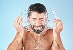 Face, splash and man in studio for cleaning, wellness and personal health with self care by blue background. Model, facial and healthy with water splash, self love and cosmetics by studio backdrop