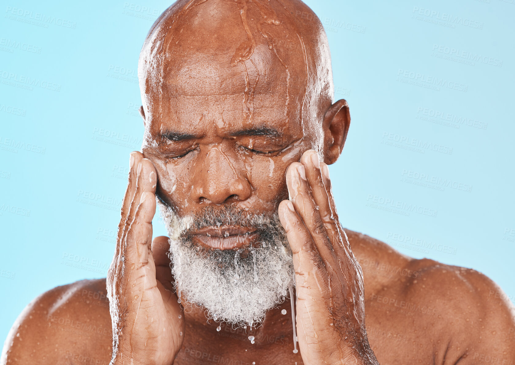 Buy stock photo Black man, face and water drip in studio for cleaning cosmetics, wellness and healthy skincare on blue background. Male model, water splash and wet shower for facial beauty, aesthetic and self care