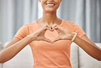 Sofa, happy and woman with a heart symbol while relaxing in the living room of her modern home. Happiness, smile and girl model hands with a love sign for support, unity or trust sitting in her house