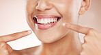 Smile, mouth and woman pointing to teeth on studio background for wellness, aesthetic beauty and healthy cosmetics. Closeup model showing clean dental skin, fresh breath and teeth whitening results
