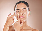 Skincare, pimple and breakout with a model black woman in studio on a beige background to pop a zit. Hand, facial and cleaning with an attractive young female examining her skin for any blemish