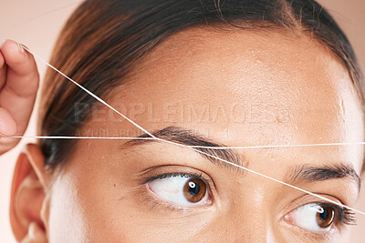 Buy stock photo Threading, eyebrows and beauty with a model black woman in studio on a beige background for hair removal. Eyes, zoom and wellness with an attractive young female using a product on her face