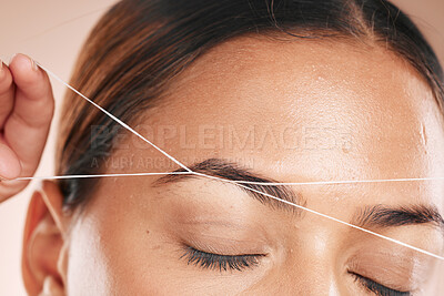 Buy stock photo Eyebrows, grooming and woman threading hair on face for beauty routine, shaping and cosmetics care on a studio background. Zoom, trimming and cosmetic model cleaning facial hair with a thread
