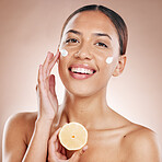 Face, cream and woman with lemon for natural beauty, cosmetics or healthy glow in studio product advertising. Young model in happy portrait for vitamin c sunscreen, dermatology and facial promotion