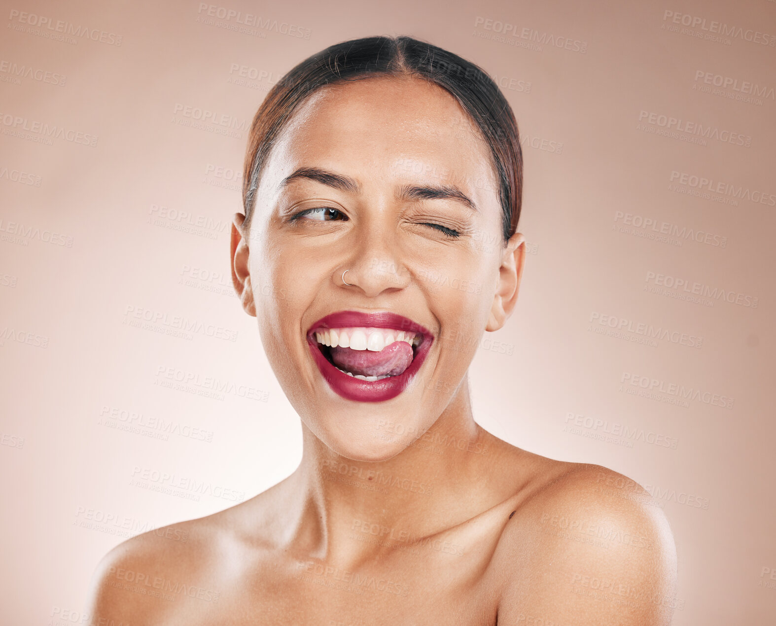 Buy stock photo Makeup, beauty and lipstick on a woman with tongue on teeth for cosmetics on a studio background for dermatology, color and salon mockup. Face of aesthetic model with a smile, glow and healthy skin