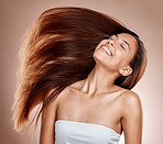 Hair care, beauty and woman in a studio with healthy, long and brown hair after a salon hair style. Cosmetics, happy and female model from Brazil with a keratin or botox treatment by brown background