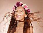 Woman, portrait and flowers on crown, studio background and windy hair for healthy skincare in Brazil. Happy face, floral headband and model of beauty, spring fashion and natural makeup of eco plants