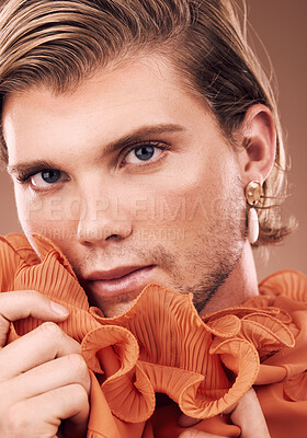 Buy stock photo Lgbtq, fashion and portrait of man with makeup, beauty and creative orange clothes on studio background. Transgender, face and queer model with skincare cosmetics, gay pride and non binary identity